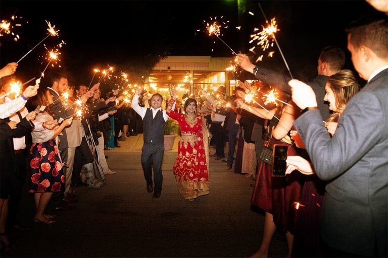 Newlyweds walking down the aisle with guests holding sparklers