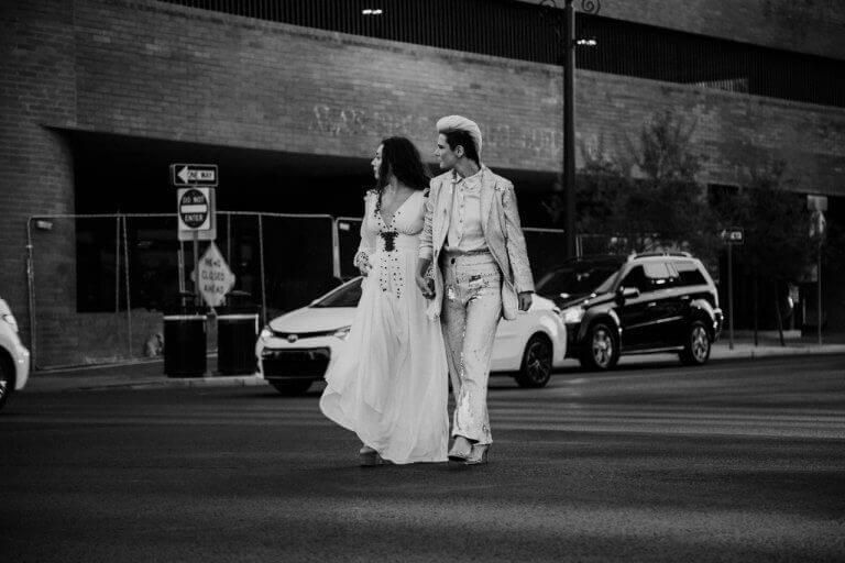 A wedding couple holding hands and walking down the street