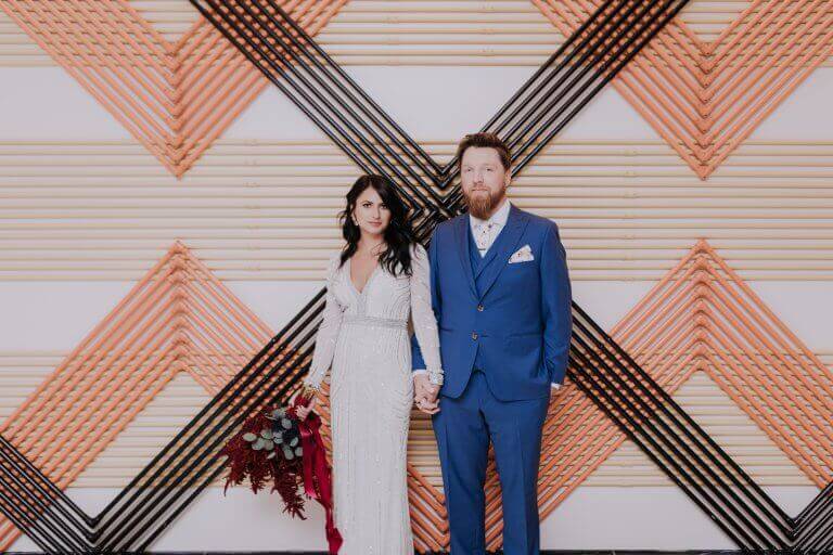 A newlywed couple stands in front of wall art