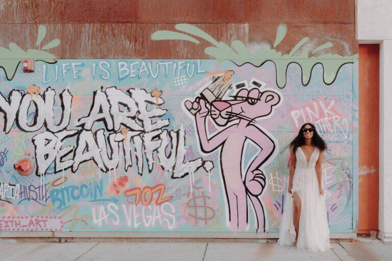 A bride poses smiling in front of street art