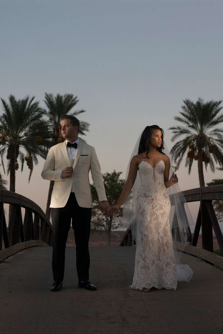 Wedding couple holding hands at dusk under palm trees