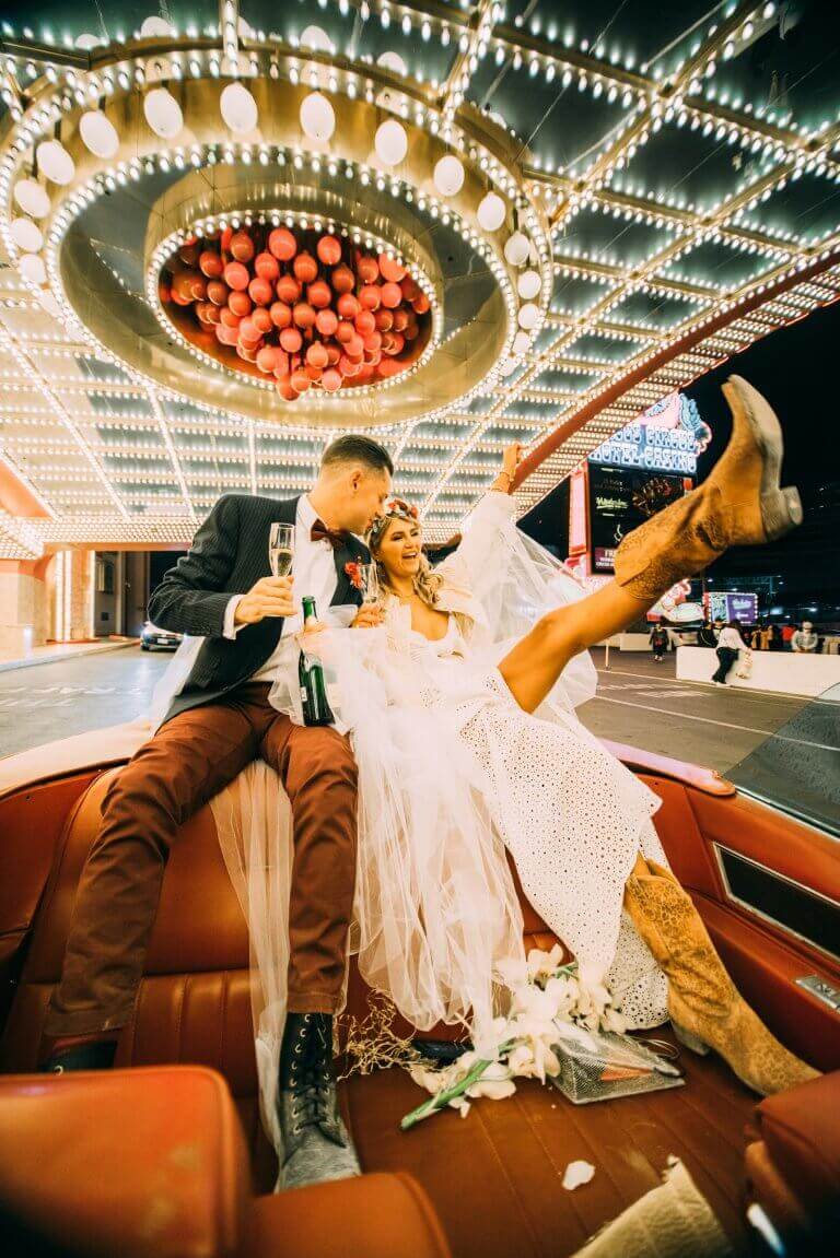 Bride and groom in western attire celebrate in a convertible limousine