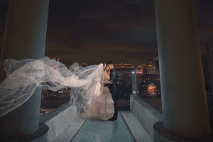A bride with a long, flowing veil and groom kissing outside with the Las Vegas skyline