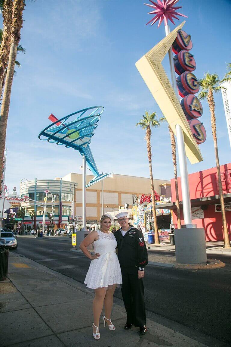 A bride and groom in a sailor's uniform pose outside in Las Vegas