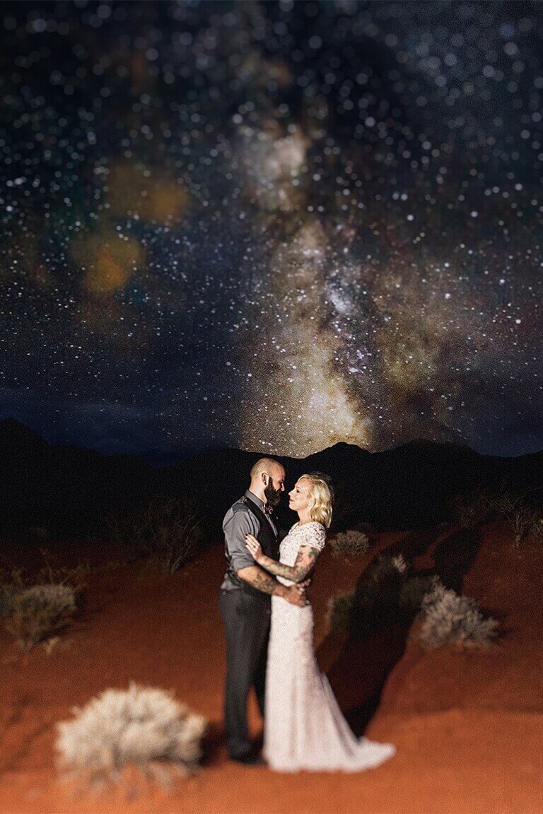 Newlyweds pose in the desert at night with a Milky Way backdrop
