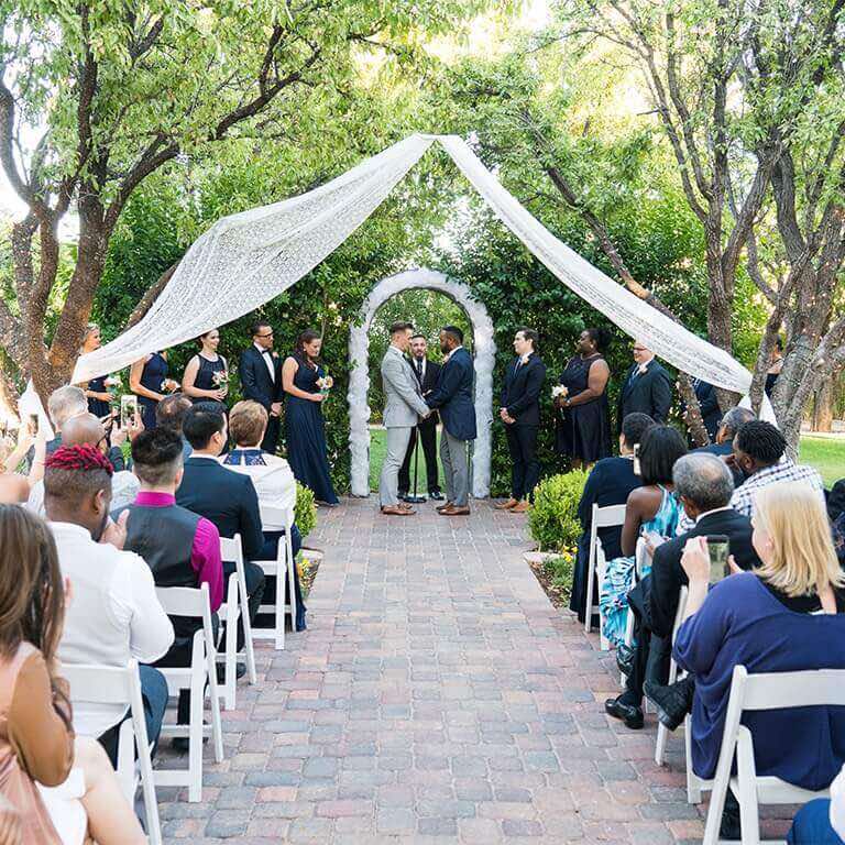 An outdoor wedding with arch and wedding guests