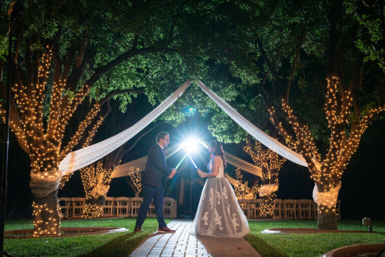 A couple in a lighted outdoor wedding chapel at night