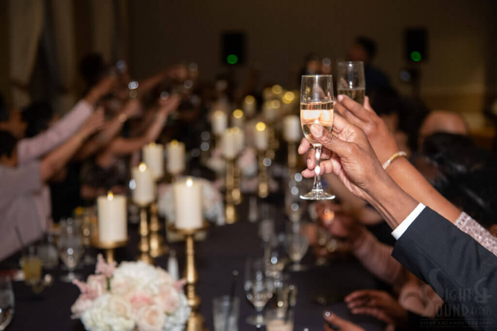 two hands holding champagne flutes at a wedding