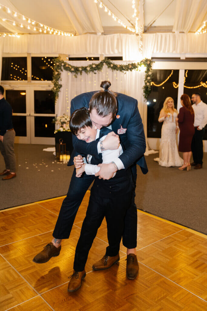 groom hugs one of the children guests at a wedding