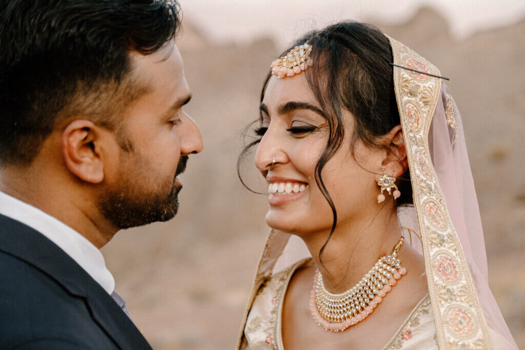 A bride with blush pink and gold Indian wedding attire with her groom