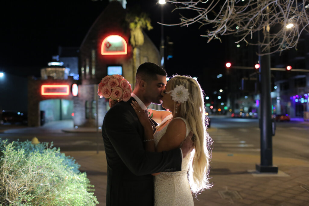 a wedding couple with a pink bouquet kisses in the dark