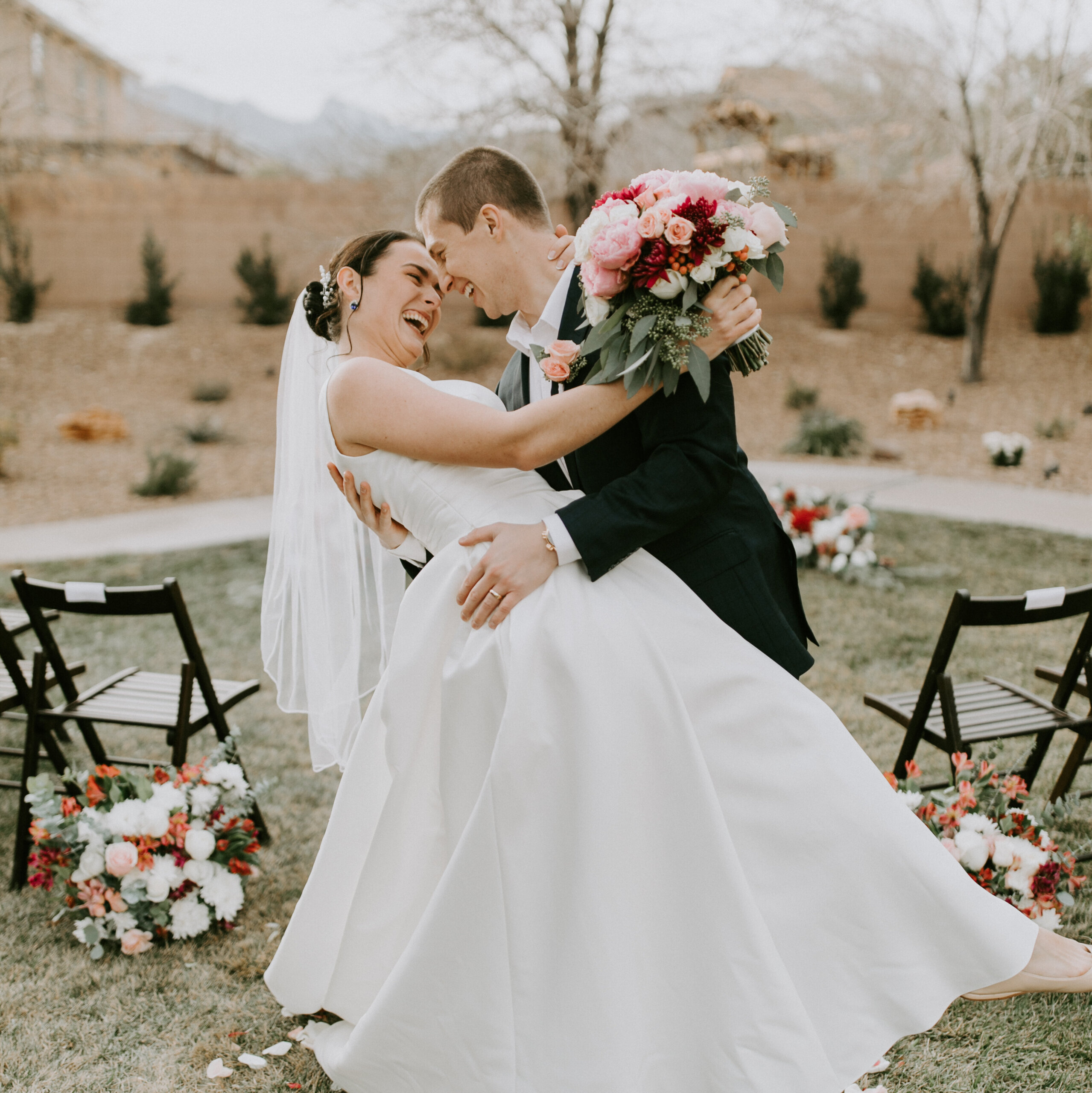 a happy couple stands in a backyard wedding aisle