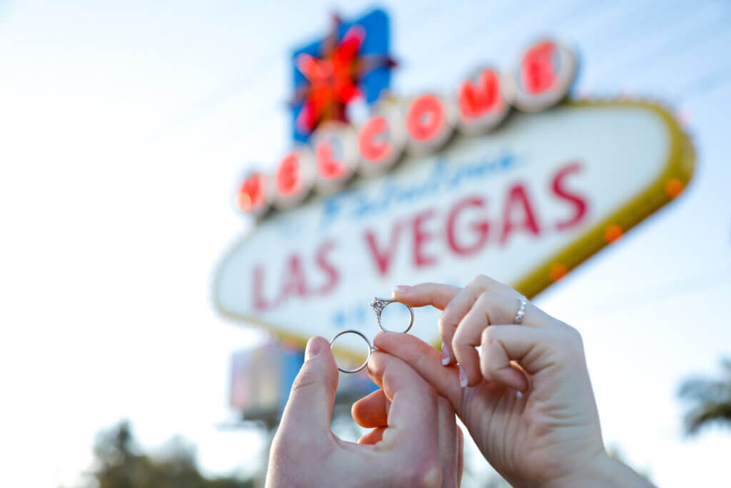 two people hold rings in front of the Las Vegas sign