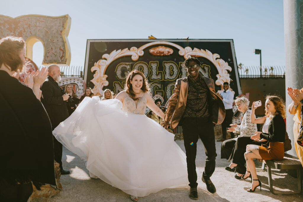 A couple runs among guests at a neon wedding