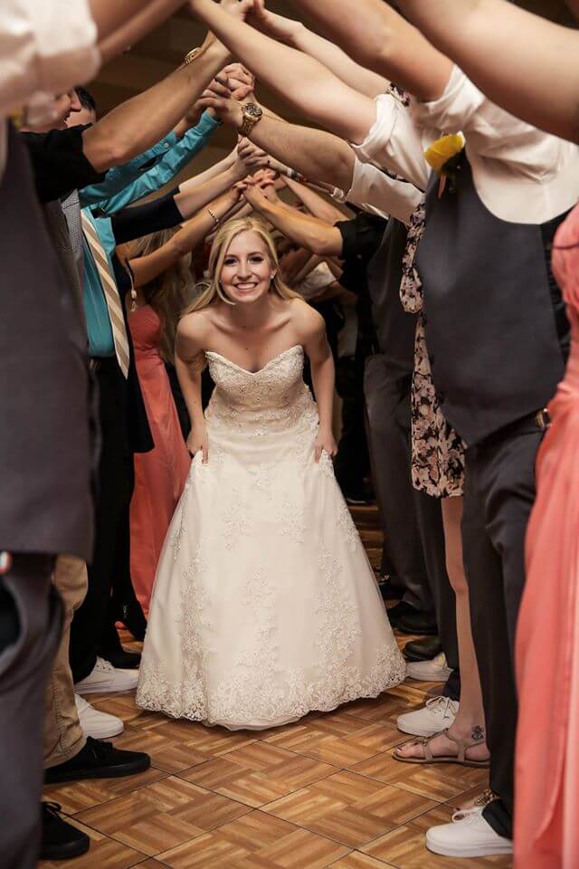 a bride goes under a tunnel of arms at her wedding