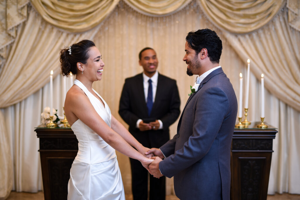 a couple happily stands at an altar with an officiant