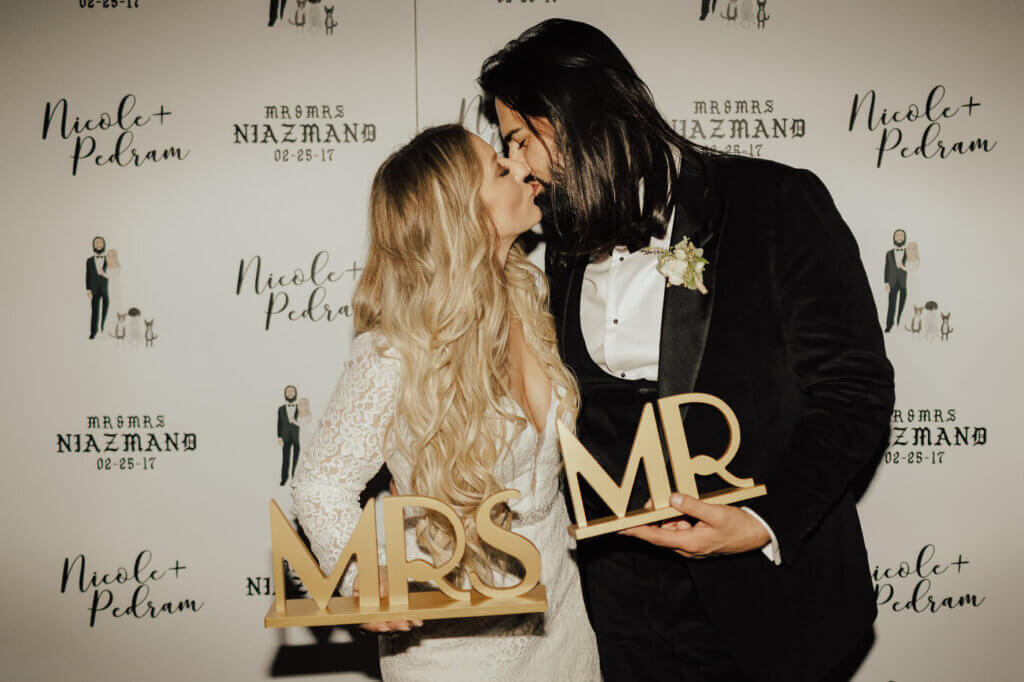 A couple holds weddings signs and kisses