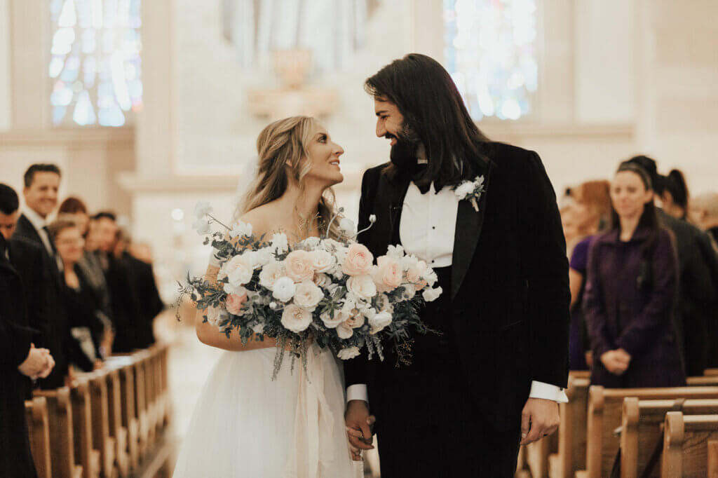 a couple in wedding apparel named Nicole and Pedram walking down the aisle