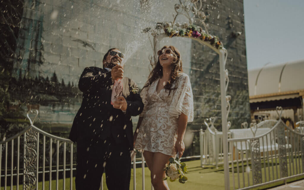 a couple popping a bottle of champagne