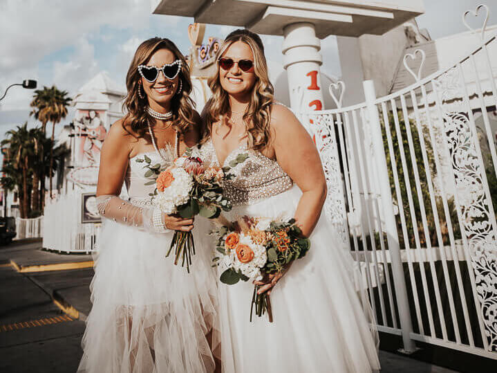 two women in wedding dresses holding flowers