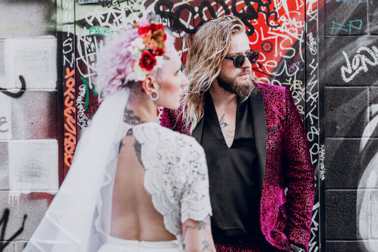 a man with blonde hair standing behind a woman in a flower veil