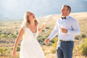 a couple laughing with drinks at a wedding