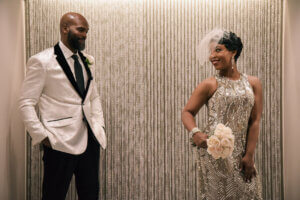 a shiny bride dress and groom in a white tux jacket