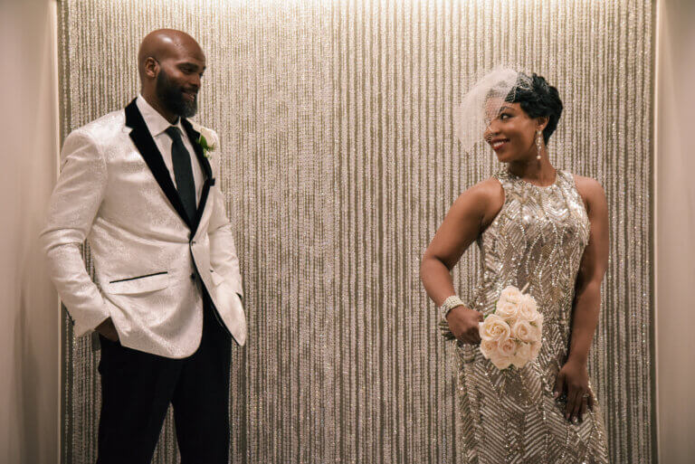a shiny bride dress and groom in a white tux jacket