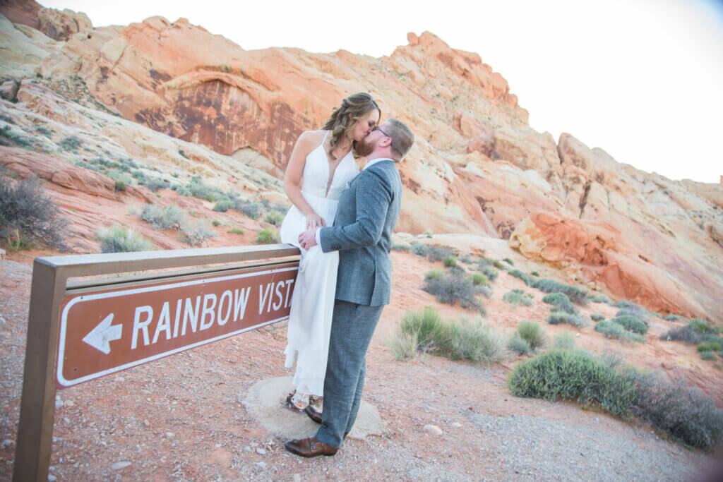 a couple kissing in Red Rock with the bride sitting on a sign
