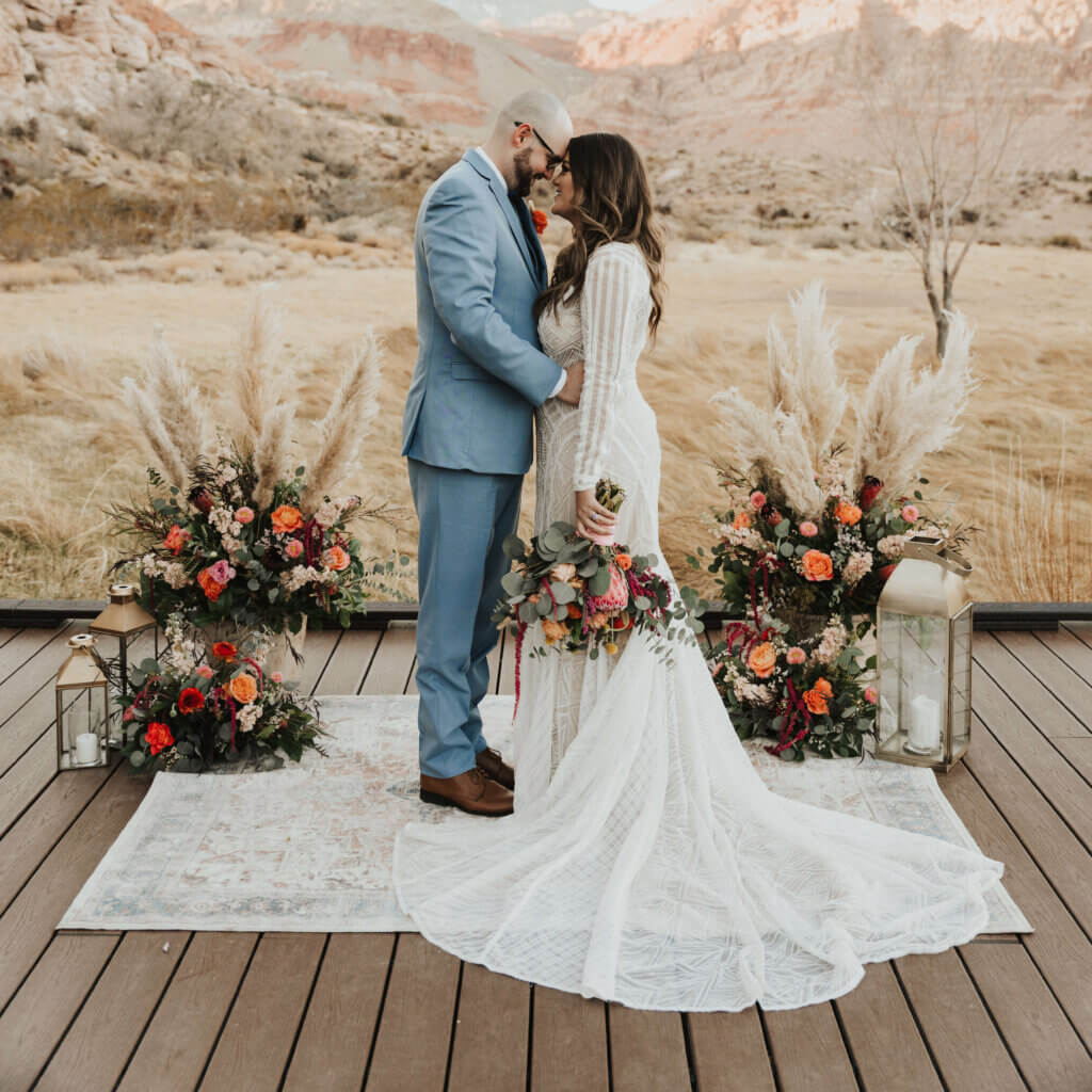 a wedding couple standing on a wood deck in a happy embrace