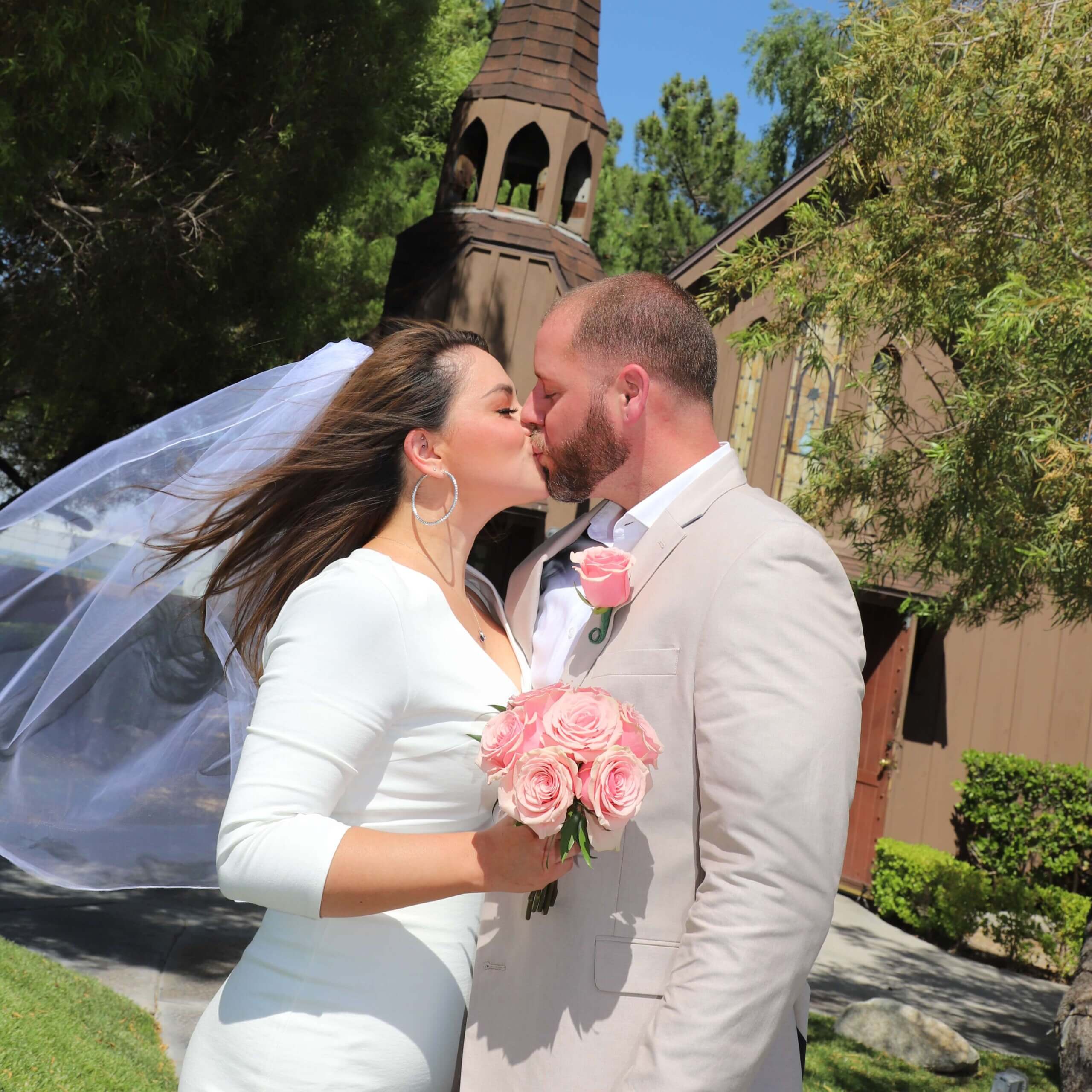 a man in a tan suit and a woman in a half-sleeve wedding dress kissing in front of a chapel. This post discusses the father wound